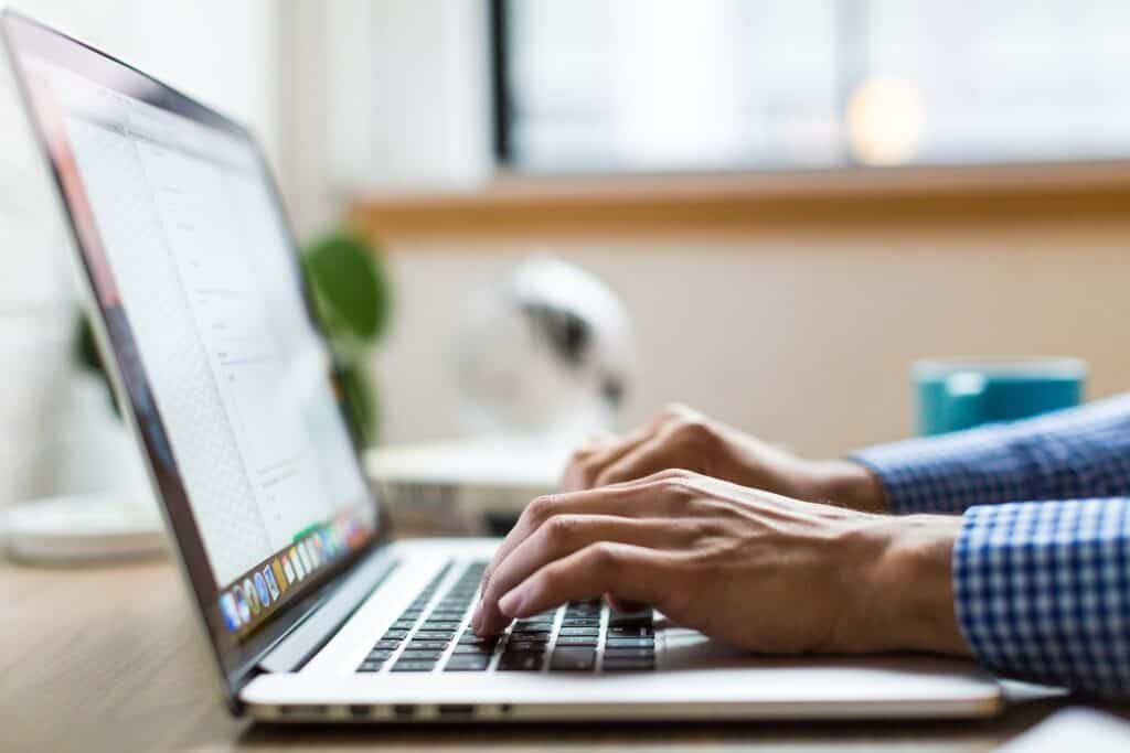 a guy typing something on a laptop