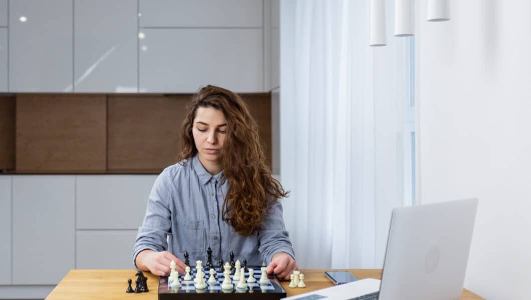 young beautiful woman using online resources to improve chess