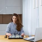 young beautiful woman using online resources to improve chess