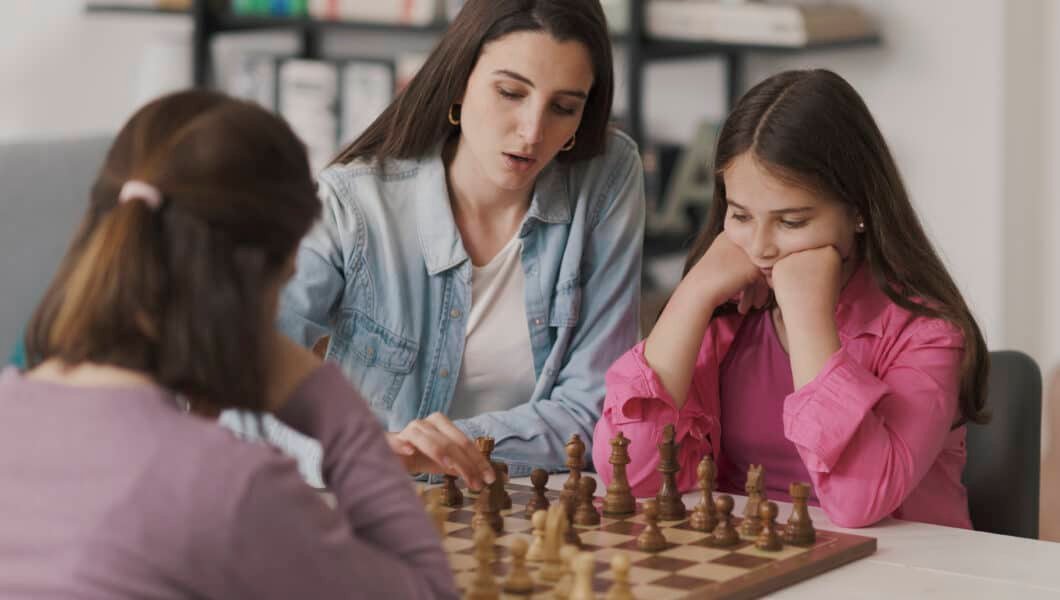 Young mother teaching chess to her kids