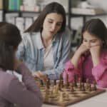 Young mother teaching chess to her kids