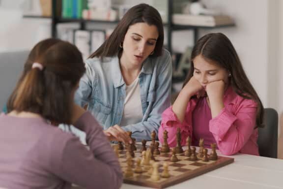 Young mother teaching chess to her kids