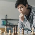 a boy thinking and trying to solve a chess puzzle