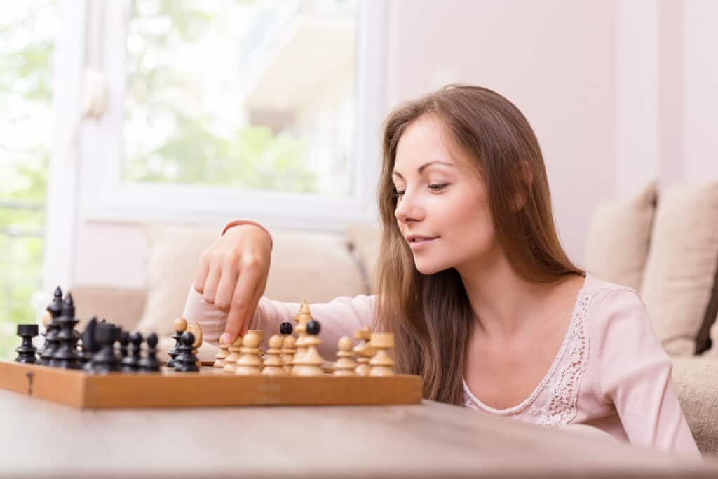 beautiful young woman smiling while making her move in a chess game