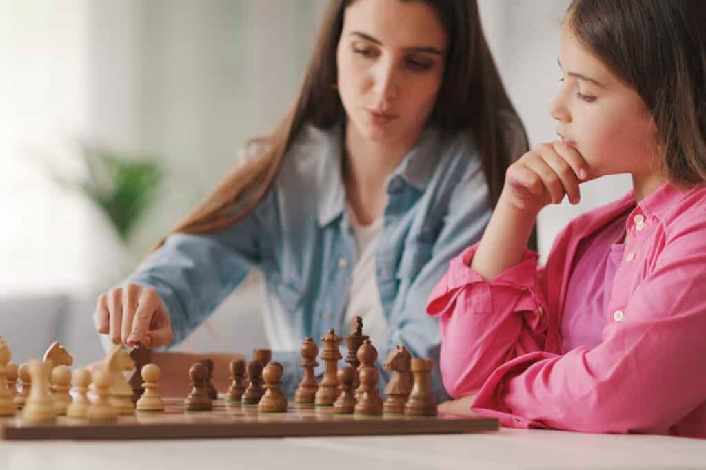 Young mother teaching chess to her kid.